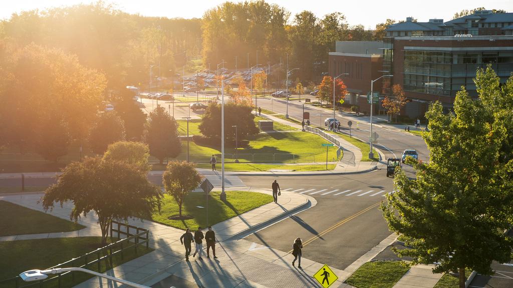 Students walk around campus beside Mason Circle at sunset.