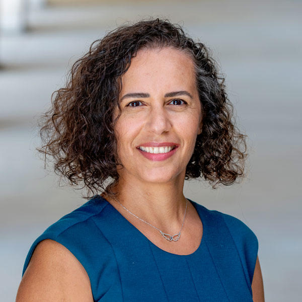 Ozlem Uzuner wears a blue dress, dark curly hair in her faculty profile for the IST department at George Mason University