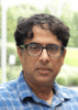 Mason professor Anand Vidyashankar wears a plaid, collared-shirt and glasses